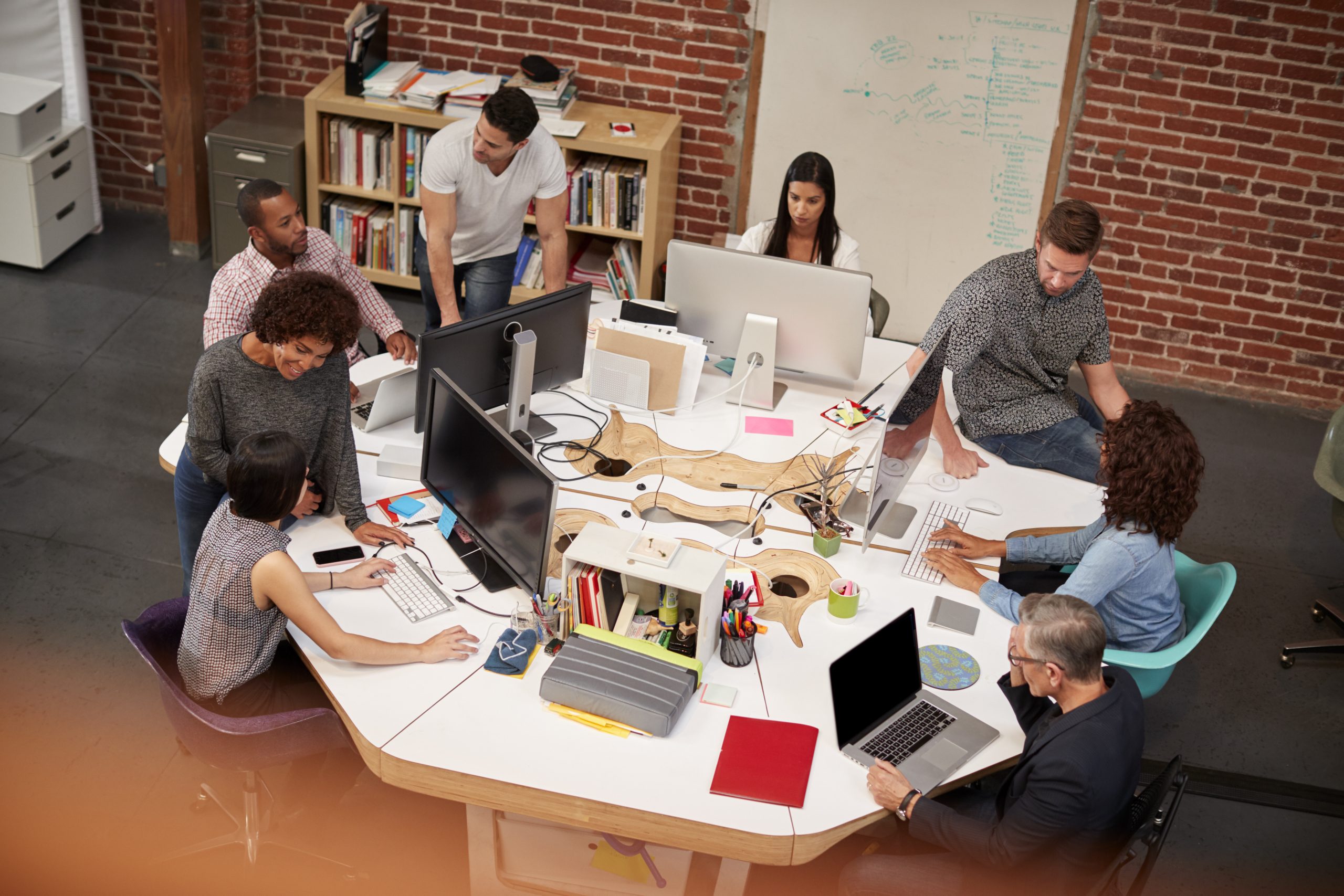 Casually Dressed Business Team Working At Desks In Modern Open Plan Office